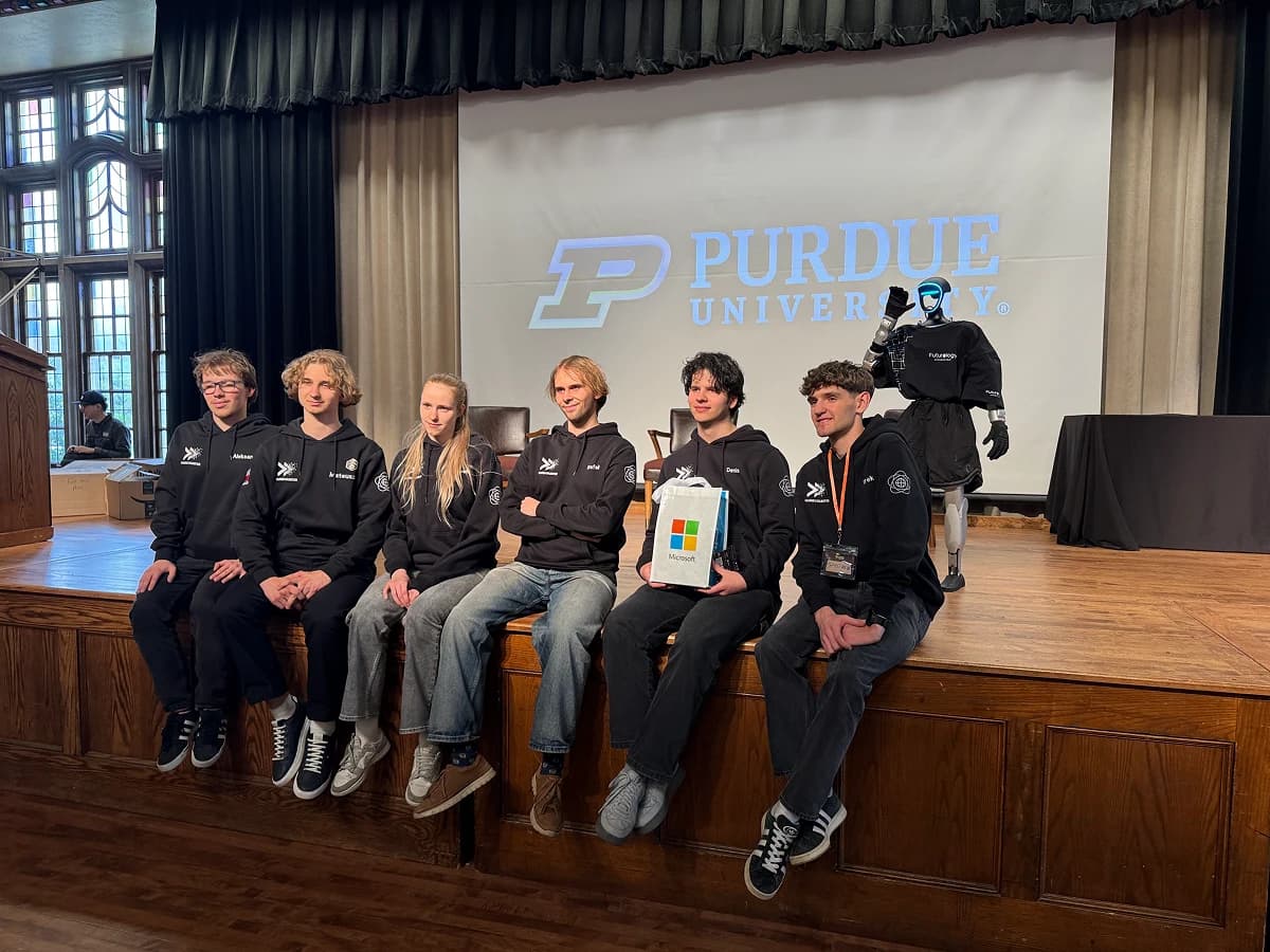 StarkHacks participants sit on a Purdue stage beside a Futurology humanoid robot
